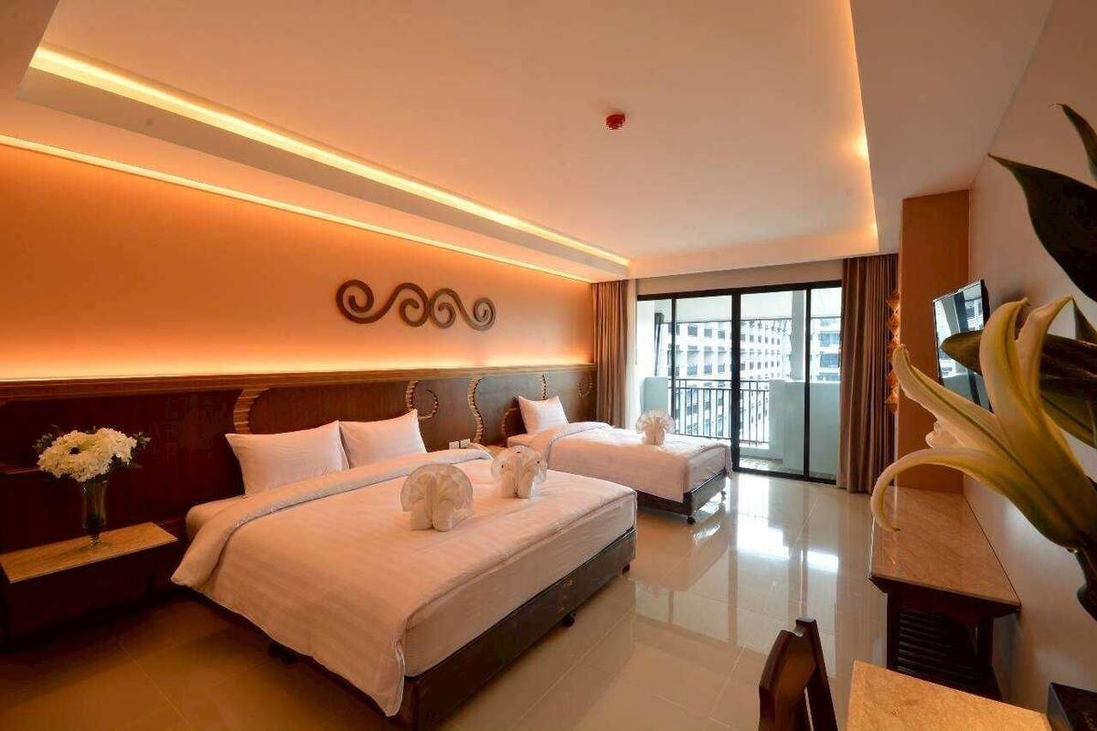 A hotel room with two beds, a large window, and a view of the city.