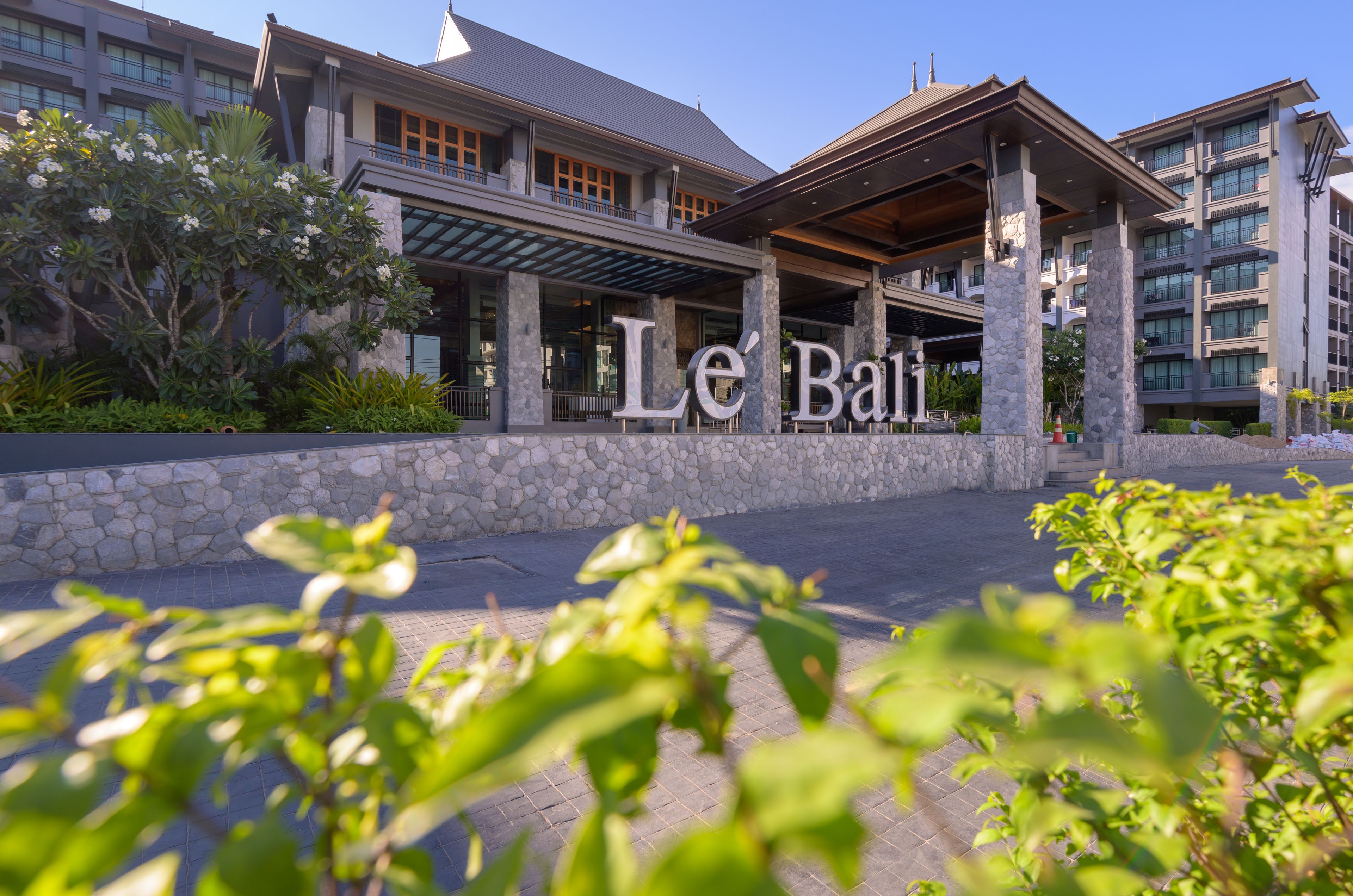 L’entrée d’un hôtel avec une façade en pierre, un espace extérieur abrité et un ciel dégagé.
