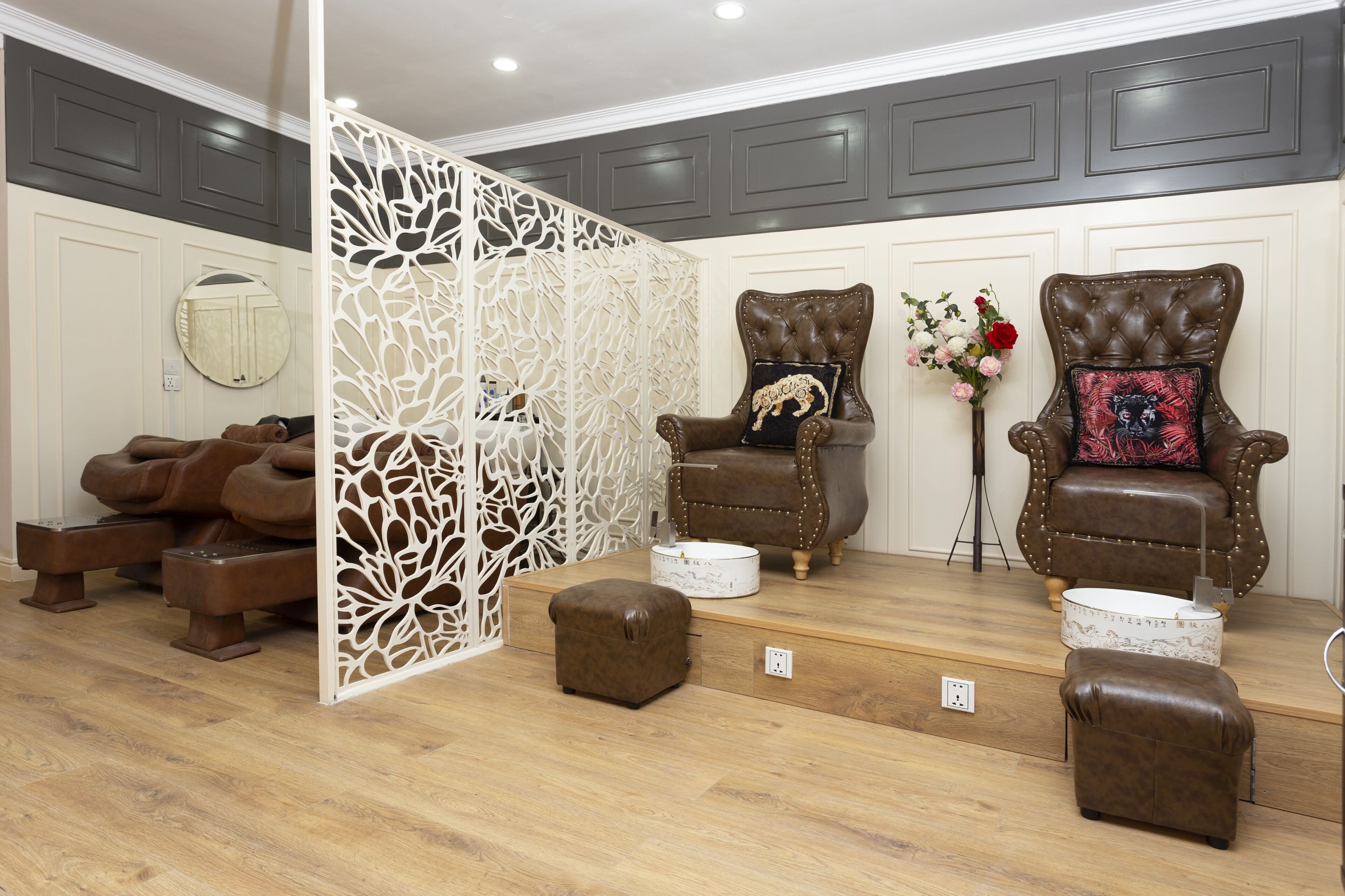 A room with two leather armchairs, a decorative white partition, and a small round table.