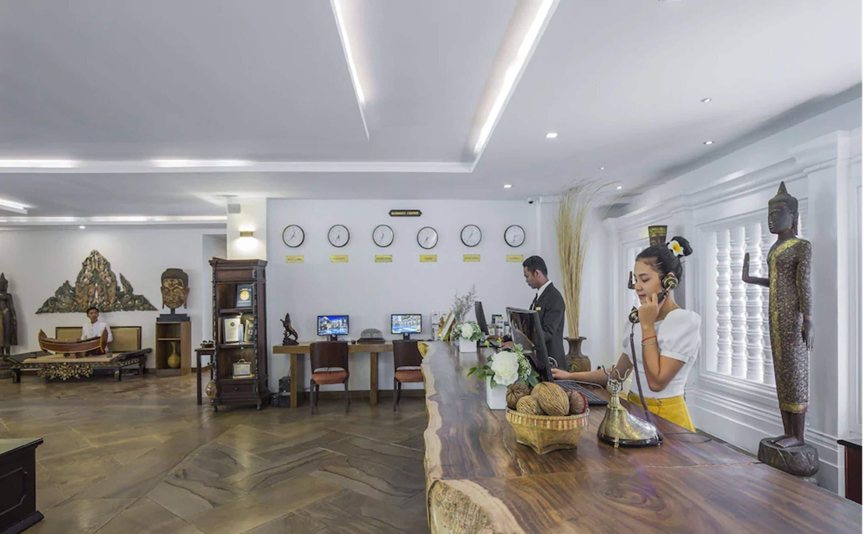 Zona de recepció amb un taulell de fusta, una estàtua de Buda i un/una recepcionista.