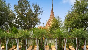 A pool area with lounge chairs and a temple in the background. - Palace Gate Hotel & Resort by EHM (Phnom Penh)