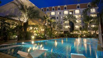 Una piscina al aire libre, sombrillas, sillones reclinables de piscina