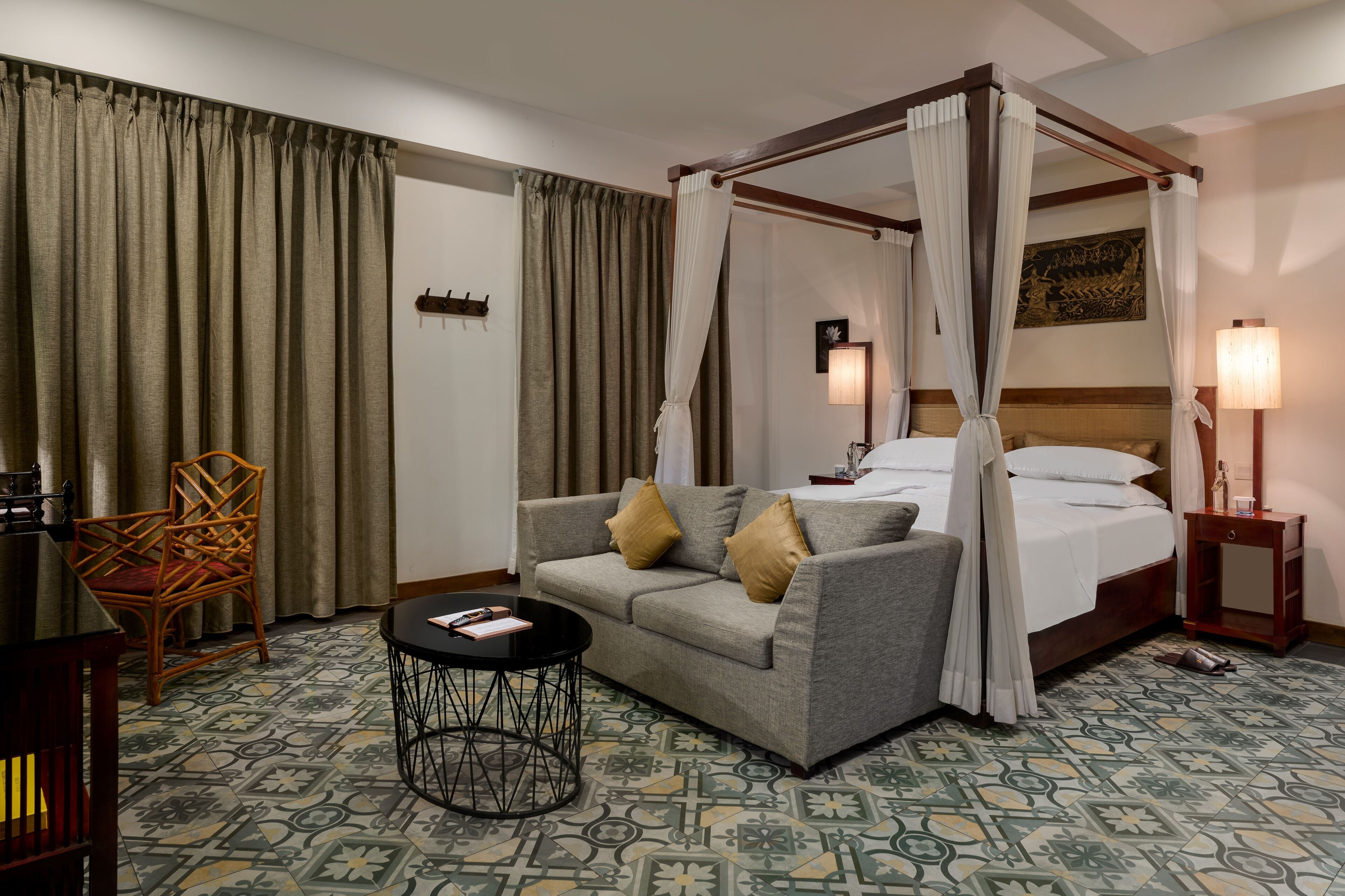 Una habitación de hotel con una cama con dosel, un sofá, una mesita y una silla.