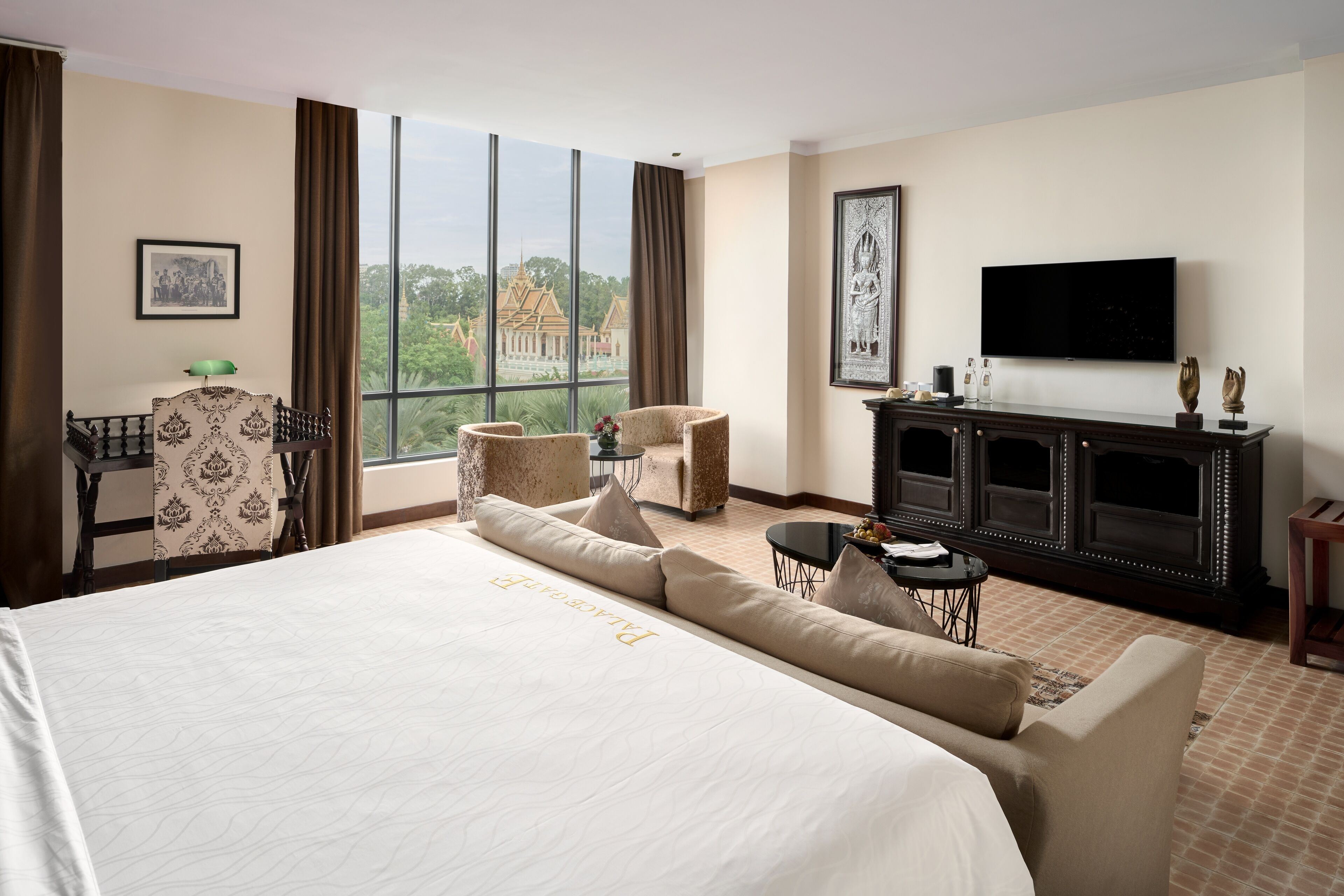 Habitación de hotel con una cama grande, un escritorio, un televisor y vistas a un templo a través de la ventana.
