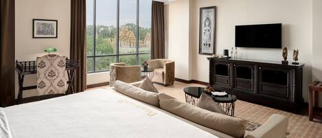 Habitación de hotel con una cama grande, un escritorio, un televisor y vistas a un templo a través de la ventana.
