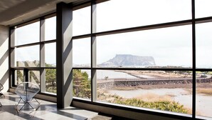 Una habitación con amplios ventanales que ofrecen vistas a un paisaje costero, incluyendo una formación rocosa destacada y una masa de agua.