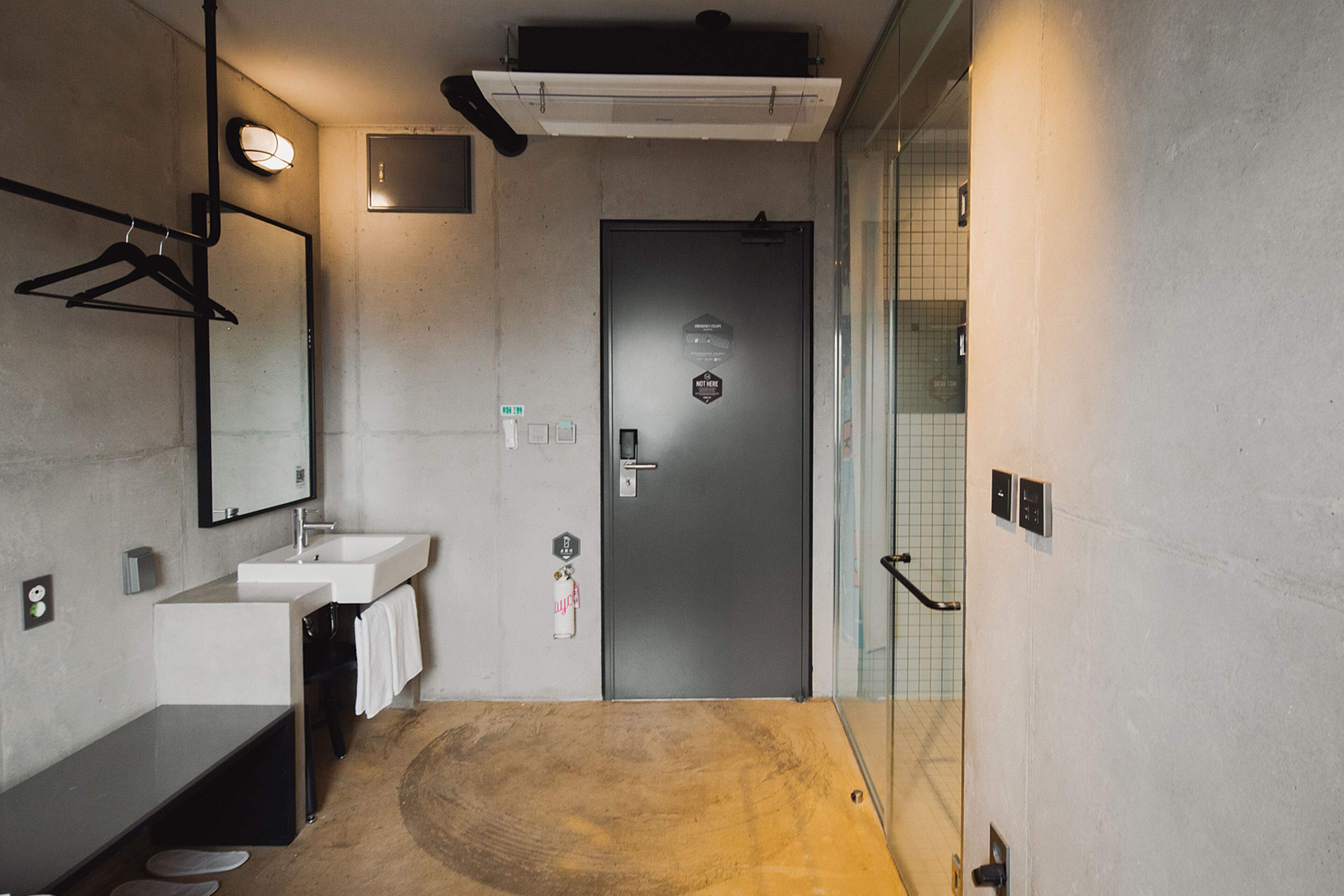 Un baño moderno con lavamanos, espejo, toallero y una puerta con un cartel.