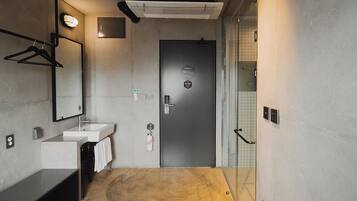 Un baño moderno con lavamanos, espejo, toallero y una puerta con un cartel.