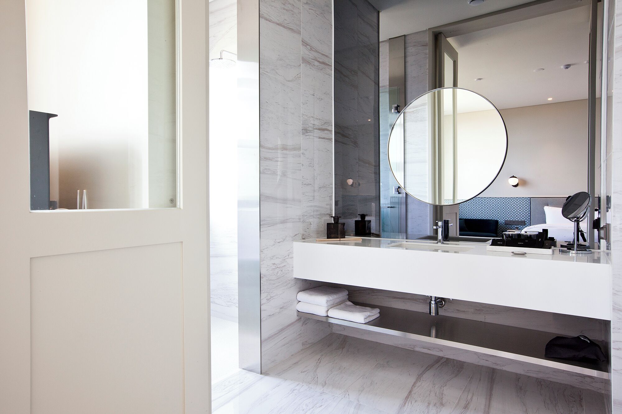 Un bagno moderno con uno specchio grande, pareti in marmo e un mobile lavabo bianco.