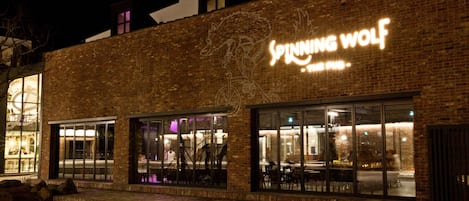 A brick building with large windows and a neon sign reading "Spinning Wolf."