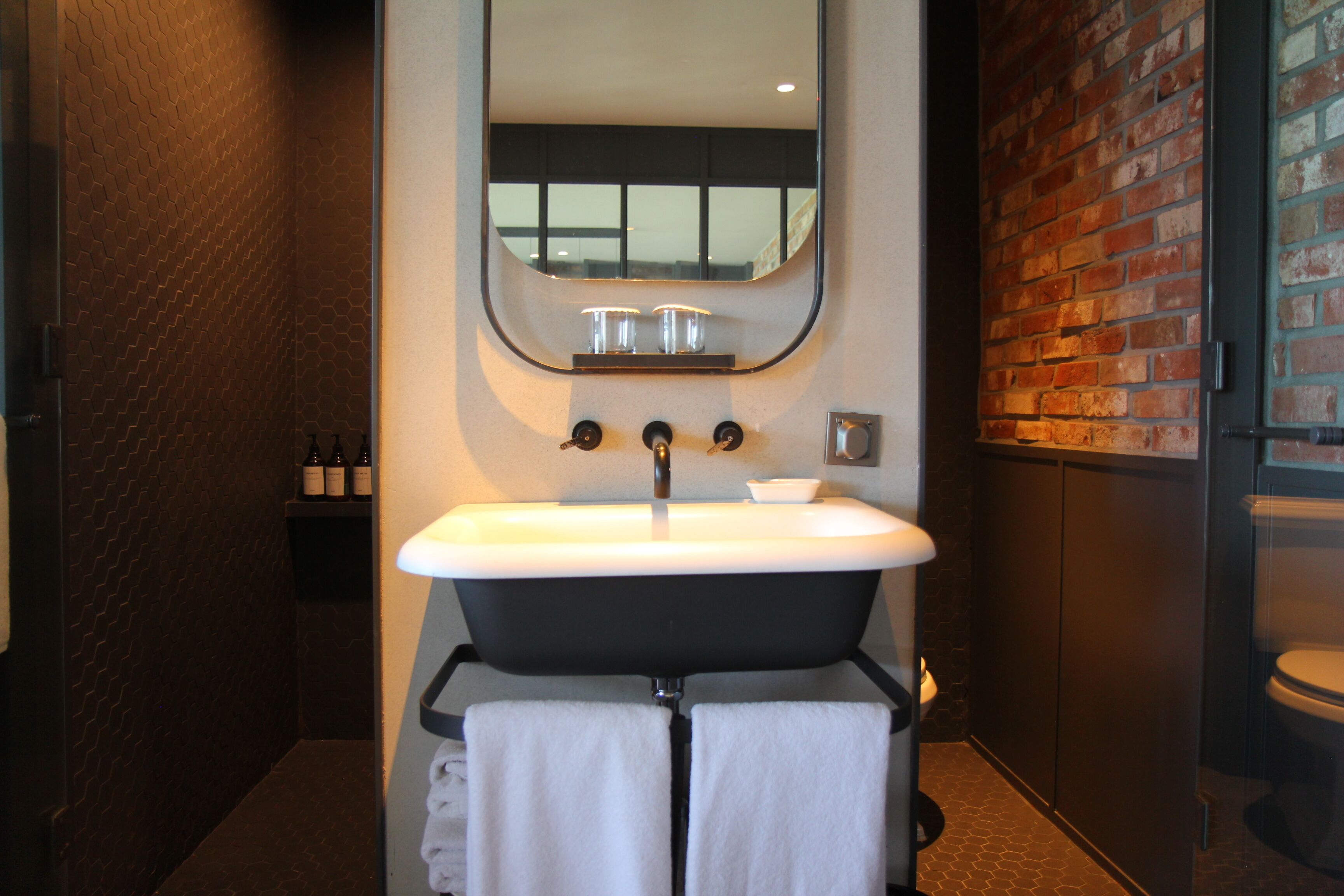 A modern bathroom with a freestanding bathtub, a large mirror, and a sink with two faucets.