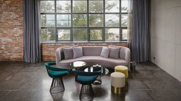 A modern living room with a gray sofa, teal and black chairs, a small round table, and a yellow ottoman.