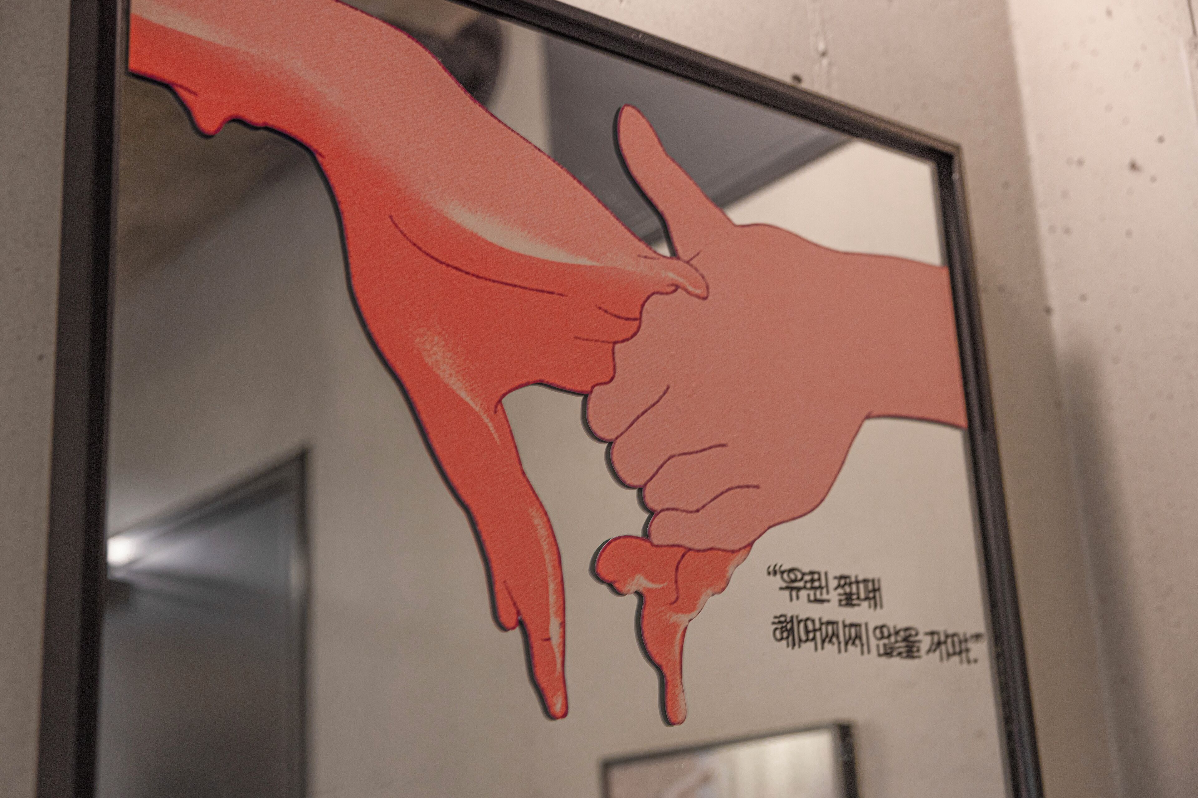A framed illustration of two hands with one pointing at the other, accompanied by text in a foreign language.