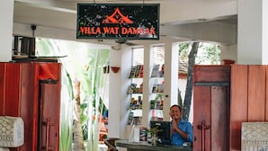 A reception desk with a sign reading "Villa Wat Damnak" and a man standing behind it. - Villa Wat Damnak (Siem Reap)