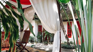 A courtyard with a checkered floor, red and white walls, and a chair. - Villa Wat Damnak (Siem Reap)