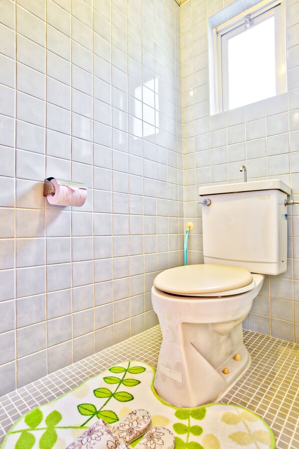 A bathroom with a toilet, a roll of toilet paper, and a window. - Pension Ilmare (Onna)