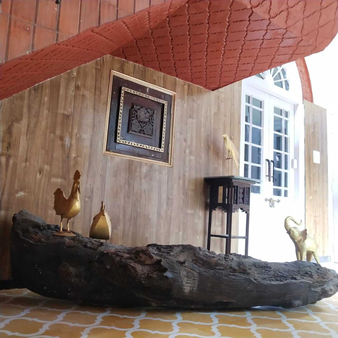 Un interior rústico con una pared de madera, un cuadro enmarcado, un gallo dorado, un cerdo dorado y una mesa negra.