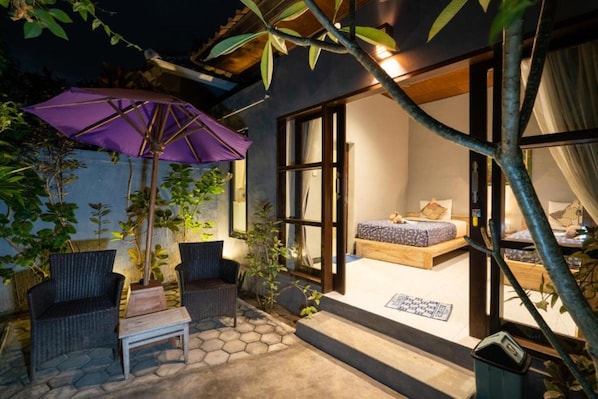 A cozy outdoor seating area with wicker furniture, a purple umbrella, and a bed with a view. - Kawans Inn Lembongan by Zuzu (Lembongan Island)