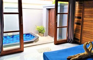 A room with a bed, a small pool, and a door leading outside. - Kawans Inn Lembongan by Zuzu (Lembongan Island)