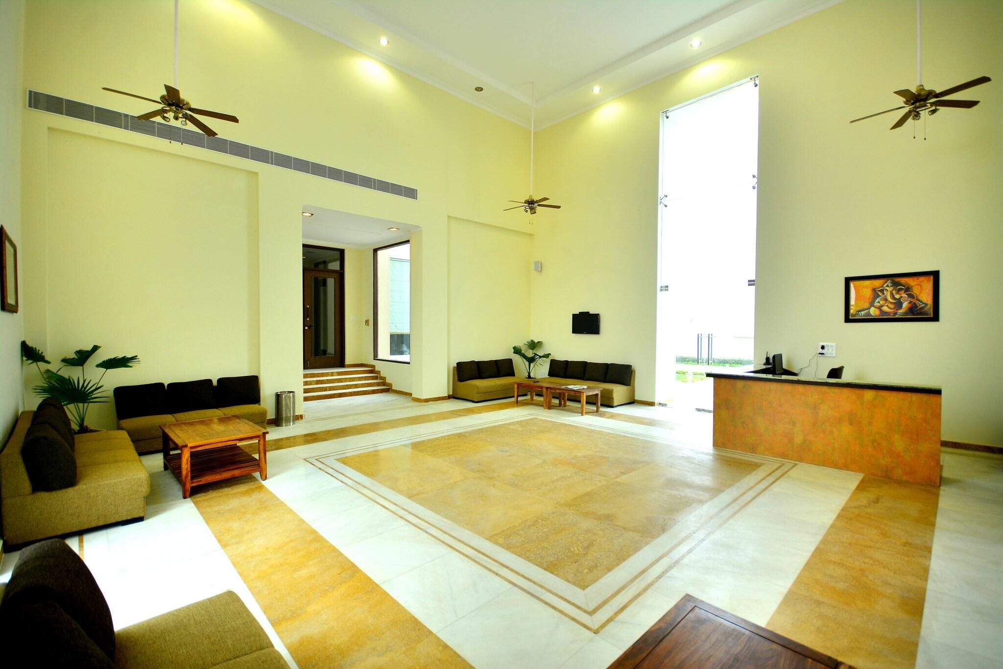 A spacious living area with a large central rug, sofas, a coffee table, and a reception desk.