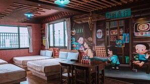 A room with two beds, a dining table, and a mural of cartoon characters. - Big Fish House (Magong)
