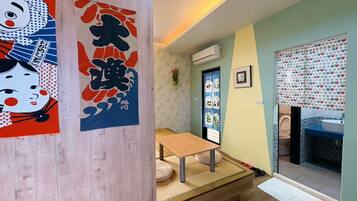 Una habitación con piso de madera, un futón de tatami, una mesita pequeña y una puerta corrediza tradicional japonesa.