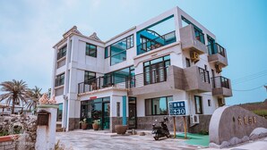 A modern multi-story building with balconies, large windows, and a sign indicating room number 230. - Big Fish House (Magong)