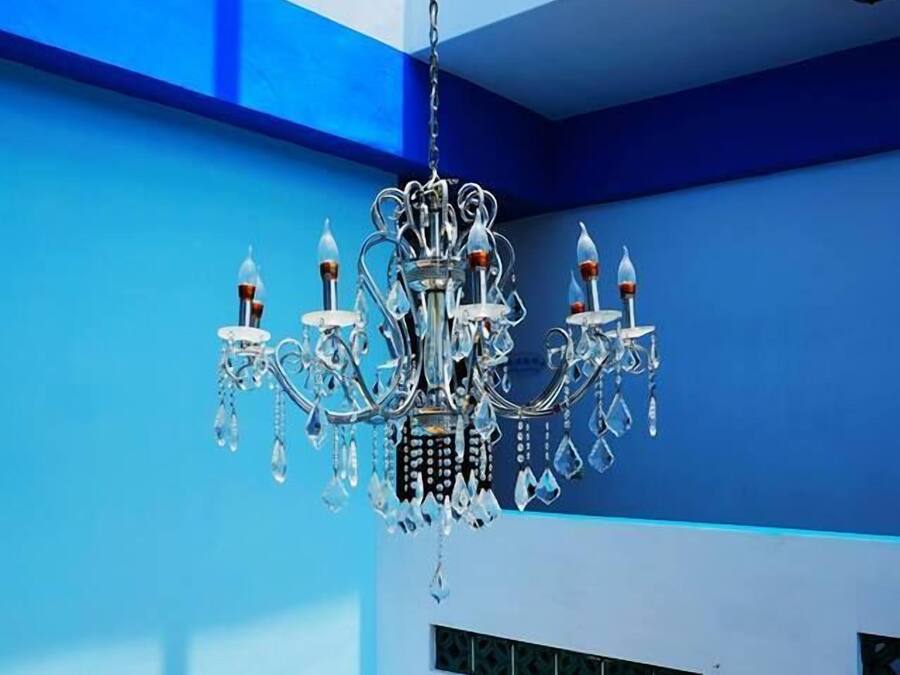 A room with a chandelier, blue walls, and a wooden floor.