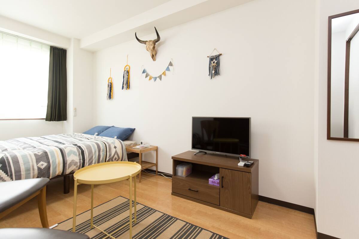Una habitación de hotel moderna con cama, televisión, una mesita y un adorno en la pared.