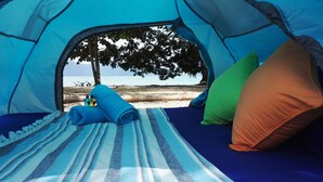 A tent with a view of the beach and trees, featuring a striped blanket, pillows, and a bottle. - Tropical Eco Camping (Langkawi)