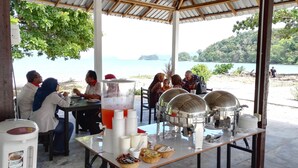 A covered dining area with tables set for a meal, a beverage dispenser, and food containers. - Tropical Eco Camping (Langkawi)
