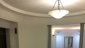 Un vestíbulo con piso de mármol, una lámpara de araña grande y un pasillo que conduce a otra habitación.