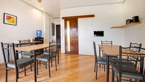 Un espace repas comprenant une table et des chaises en bois, un distributeur d’eau et un ventilateur de plafond.