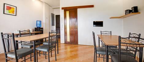 A dining area with a wooden table and chairs, a water dispenser, and a ceiling fan.