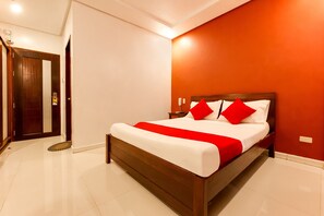 Een moderne hotelkamer met een groot bed, een houten hoofdeinde en een rode accentmuur.