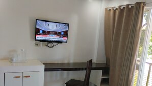 Une chambre d’hôtel équipée d’un lit, d’un bureau, d’une chaise, d’une télévision et d’une fenêtre avec des rideaux.
