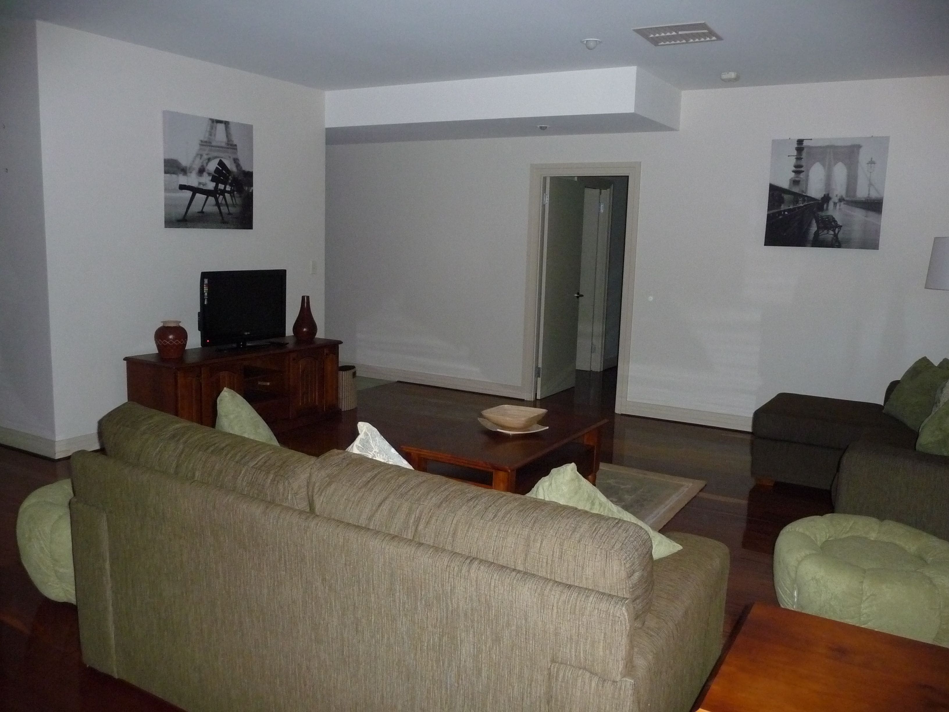 Een woonkamer met een bank, een salontafel en een televisie op een houten kast.