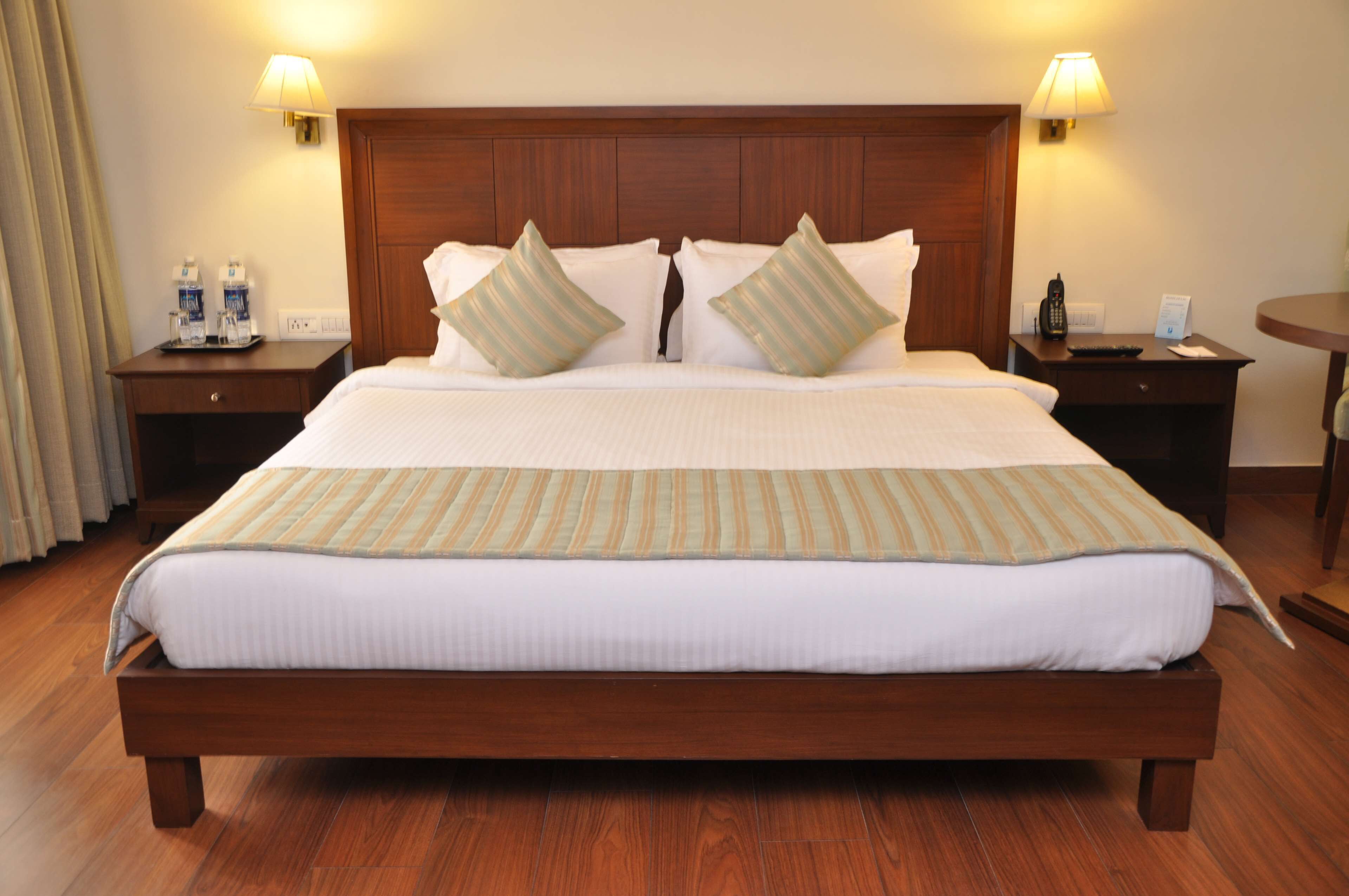 A large bed with a wooden headboard, two bedside tables with lamps, and a small round table.