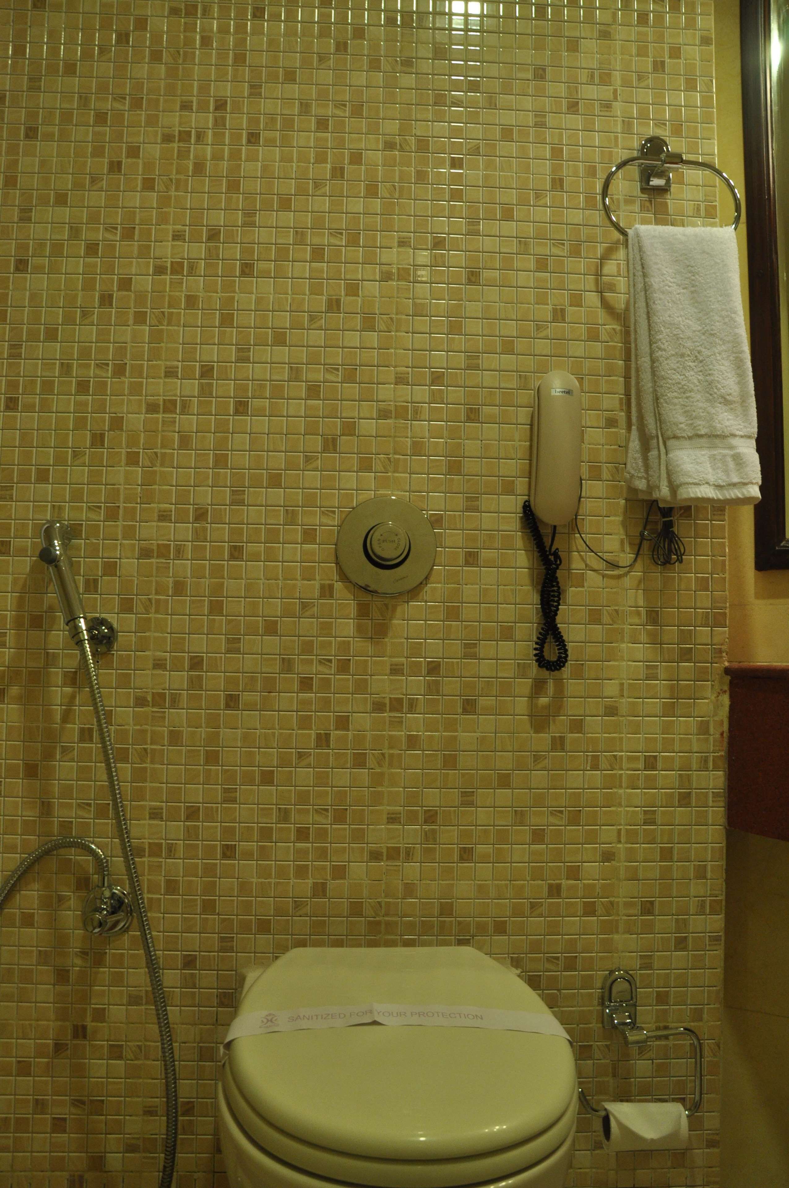 Un baño con inodoro, secamanos y toallero.
