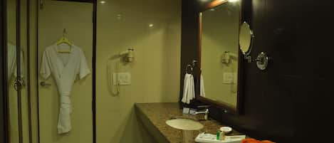 A modern bathroom with a large mirror, a sink, and a robe hanging on a rack.