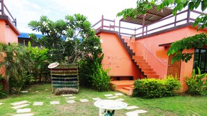 A courtyard with a palm tree, a small garden table, and a staircase leading to a balcony. - 10 Billion Resort (Samut Songkhram)
