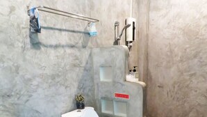 A bathroom with a toilet, sink, and a trash bin. - 10 Billion Resort (Samut Songkhram)