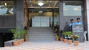 Entrada de hotel con una gran escalera, plantas en macetas y un mostrador de recepción.