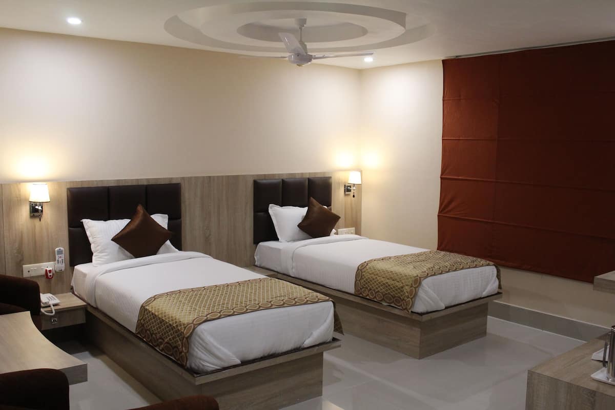 A hotel room with two beds, a desk, and a chair.