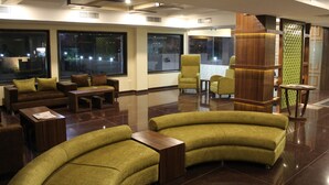 Un vestíbulo amplio con un sofá curvo, un mostrador de recepción de madera y un gran ventanal con vistas al exterior.