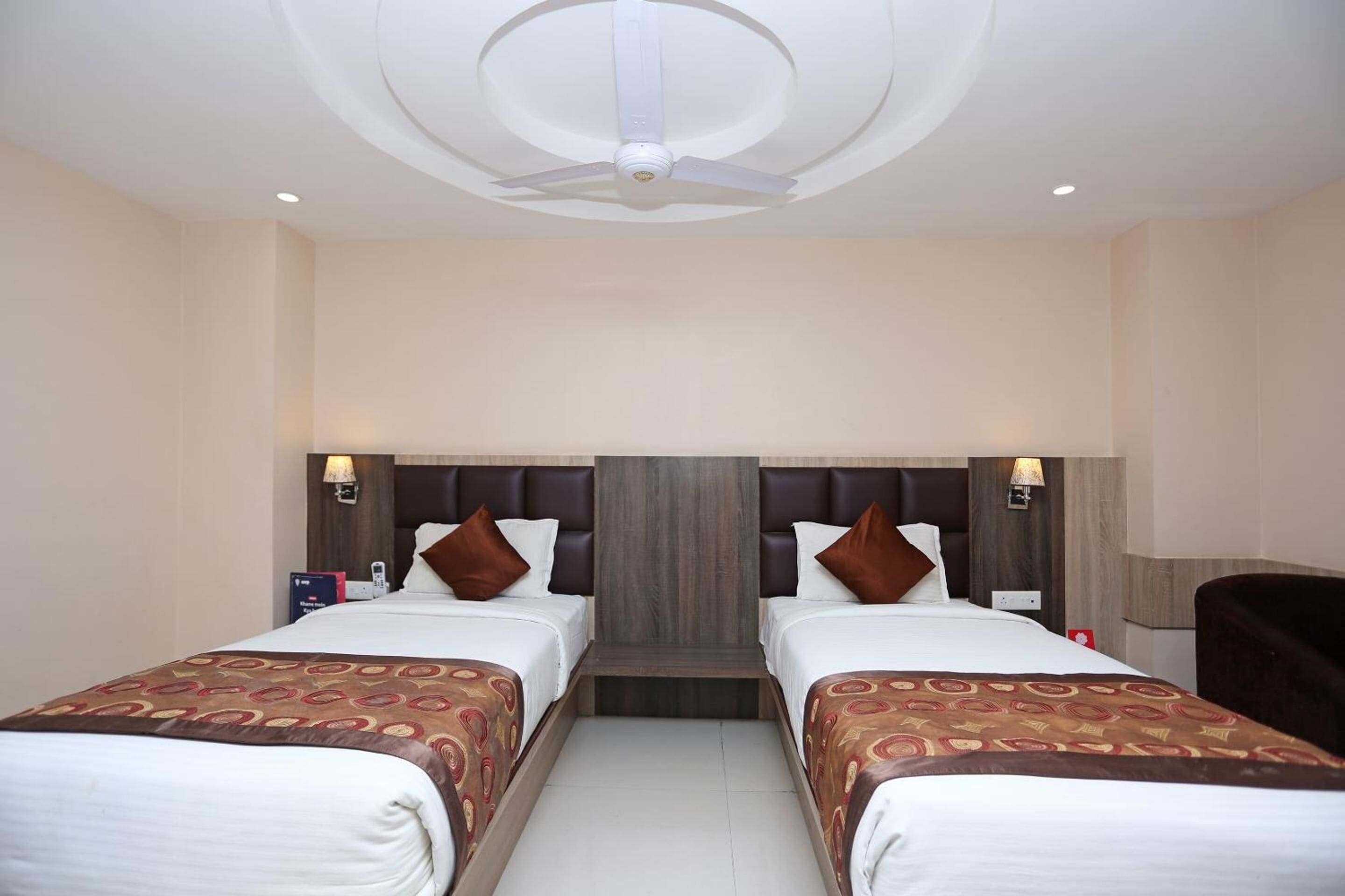 A hotel room with two beds, a ceiling fan, and a wooden headboard.