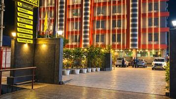 A hotel with a prominent sign, a covered entrance, and a paved driveway.