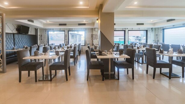 Un restaurante espacioso con varias mesas y sillas, ventanas amplias y una decoración de estilo moderno.