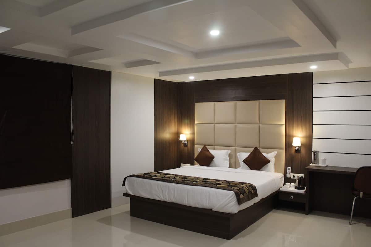 A modern hotel room with a large bed, a desk, and a chair.