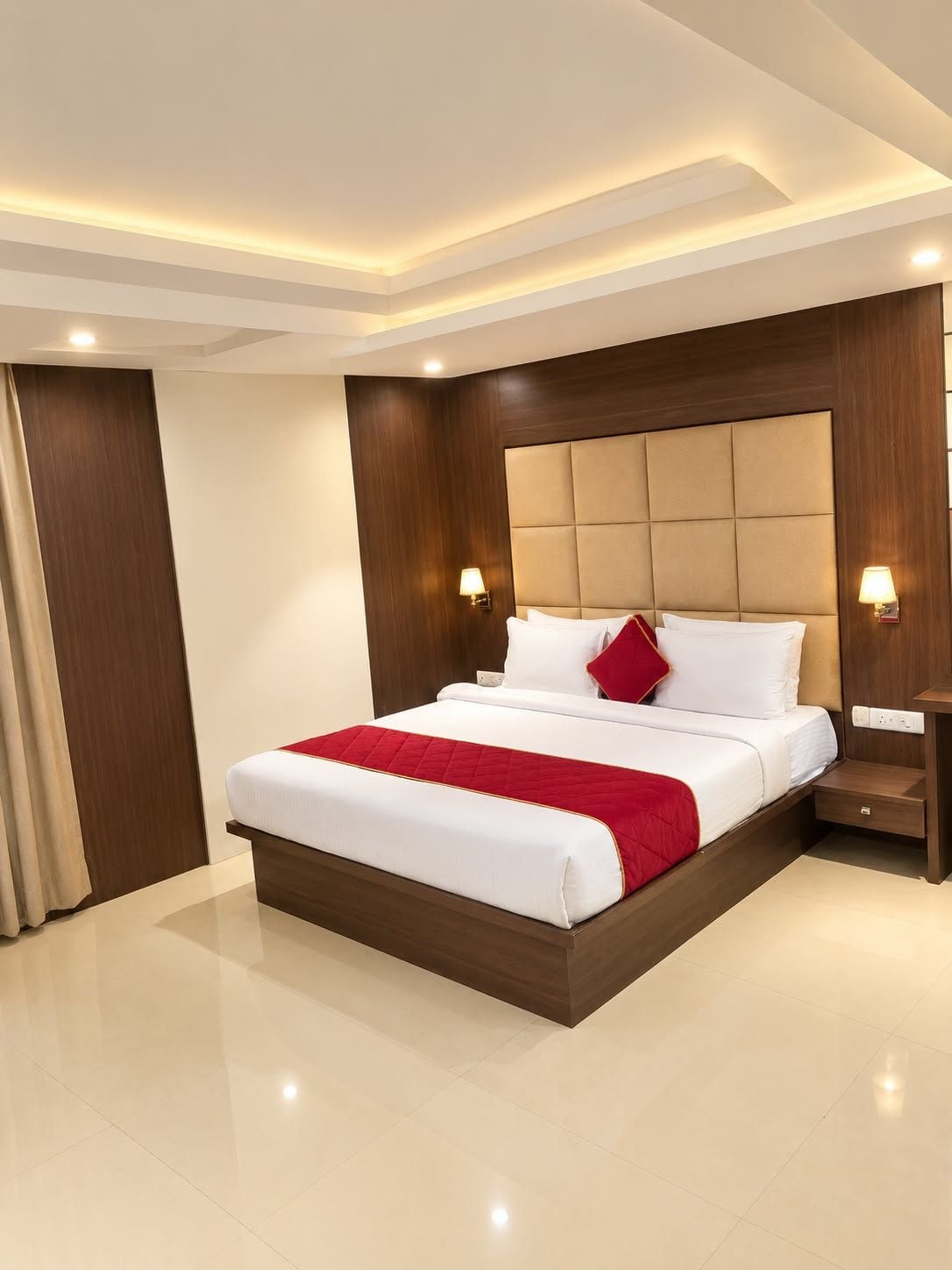 A hotel room with a large bed, a wooden headboard, two bedside lamps, and a nightstand.